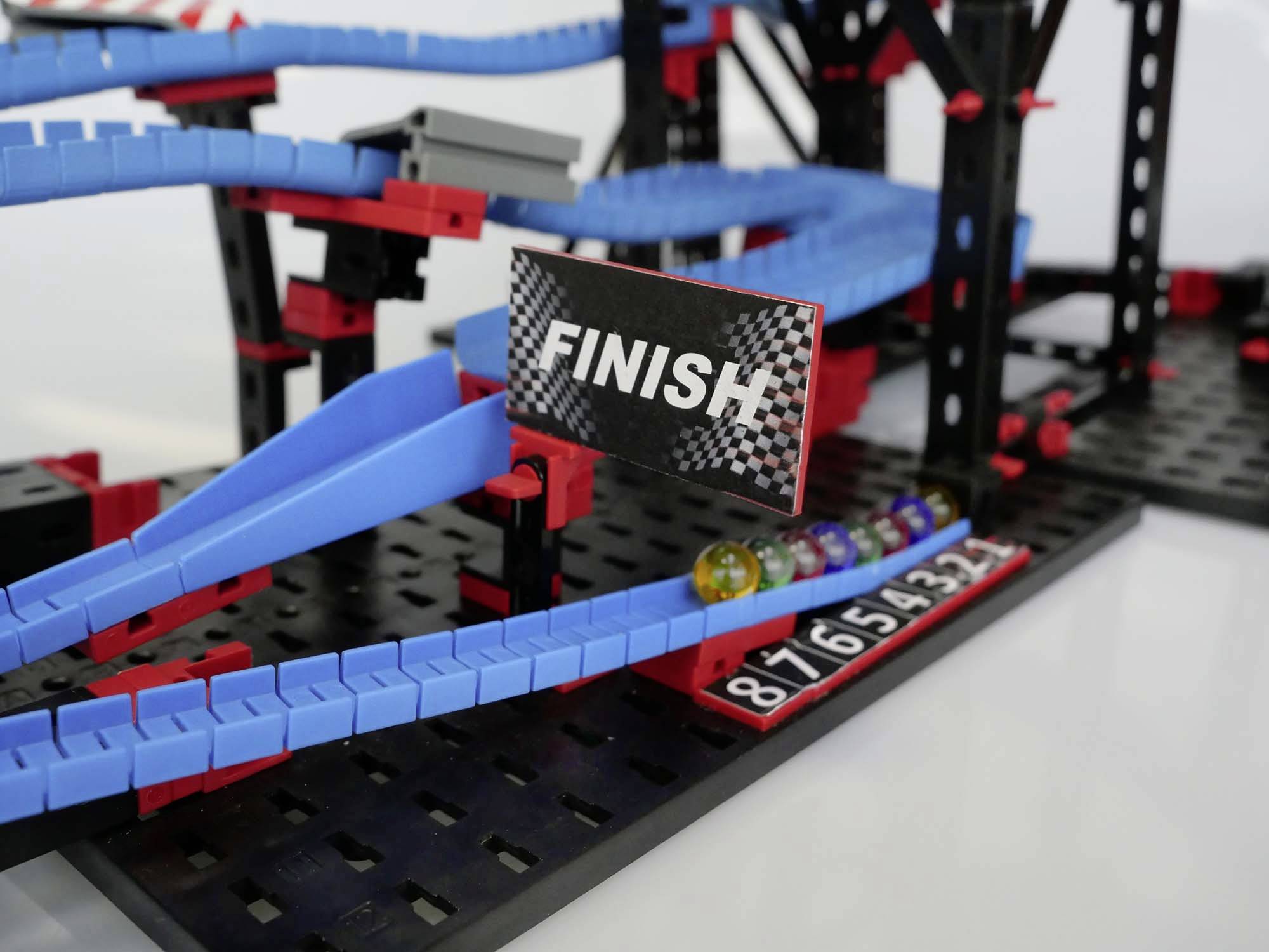 Marble run with a "Finish" sign. A marble reaches the goal, while other marbles roll along the blue track.