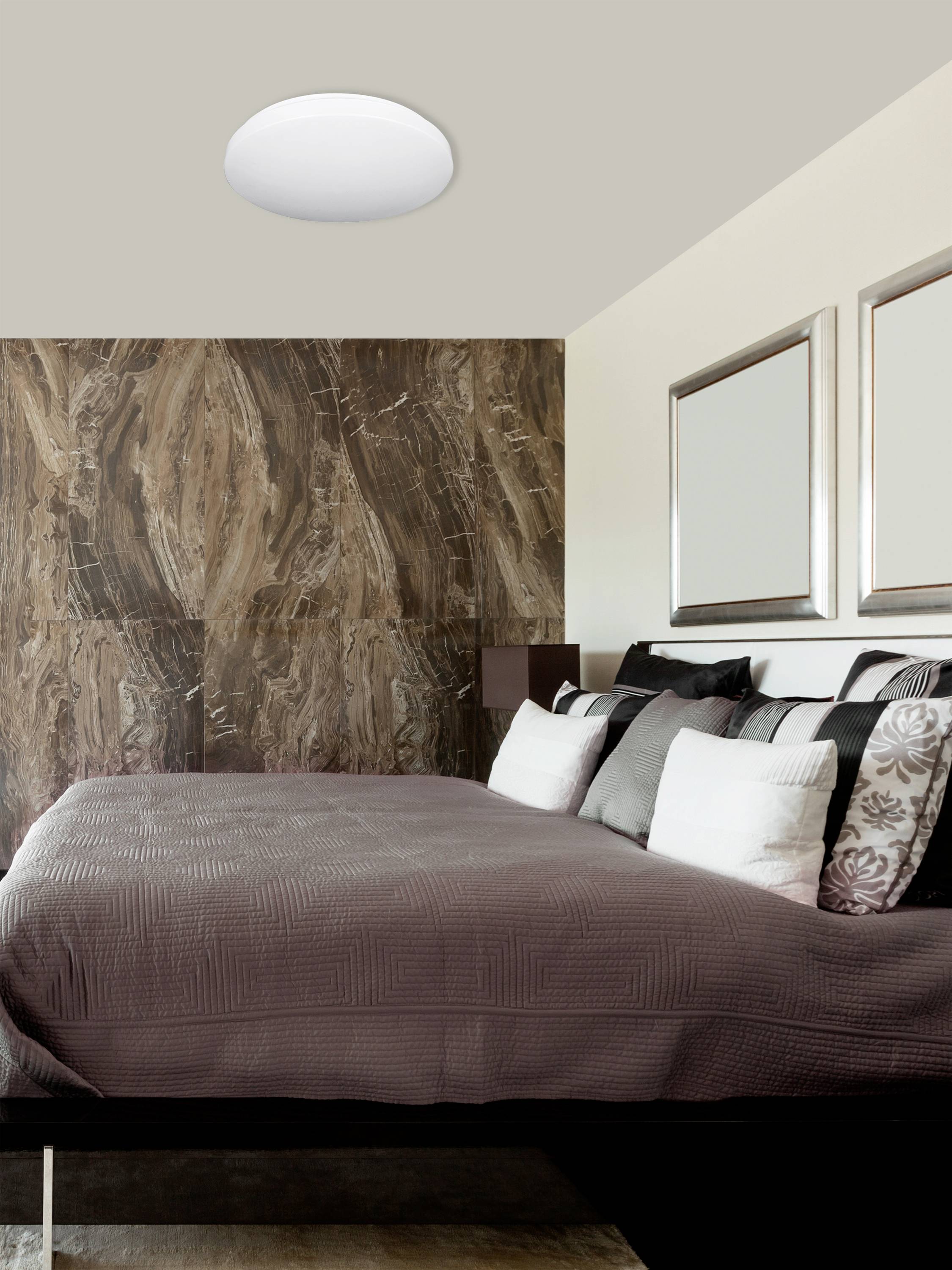 A cosy bedroom with a large bed, several pillows and wood panelling on the wall in the background.