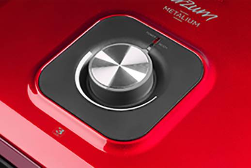 Close-up of a red, metallic rotary knob on a device, with the inscription 'METALIUM' in the top right corner.