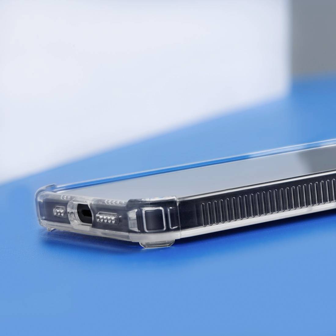 Smartphone with a transparent protective case on a blue background, lying sideways and showing the ports.