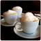 Three cups of cappuccino with milk foam are standing on saucers on a table.