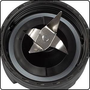 Top-down view of a metal-bladed knife in a mixer container. The blades are arranged in a cross formation to chop ingredients.