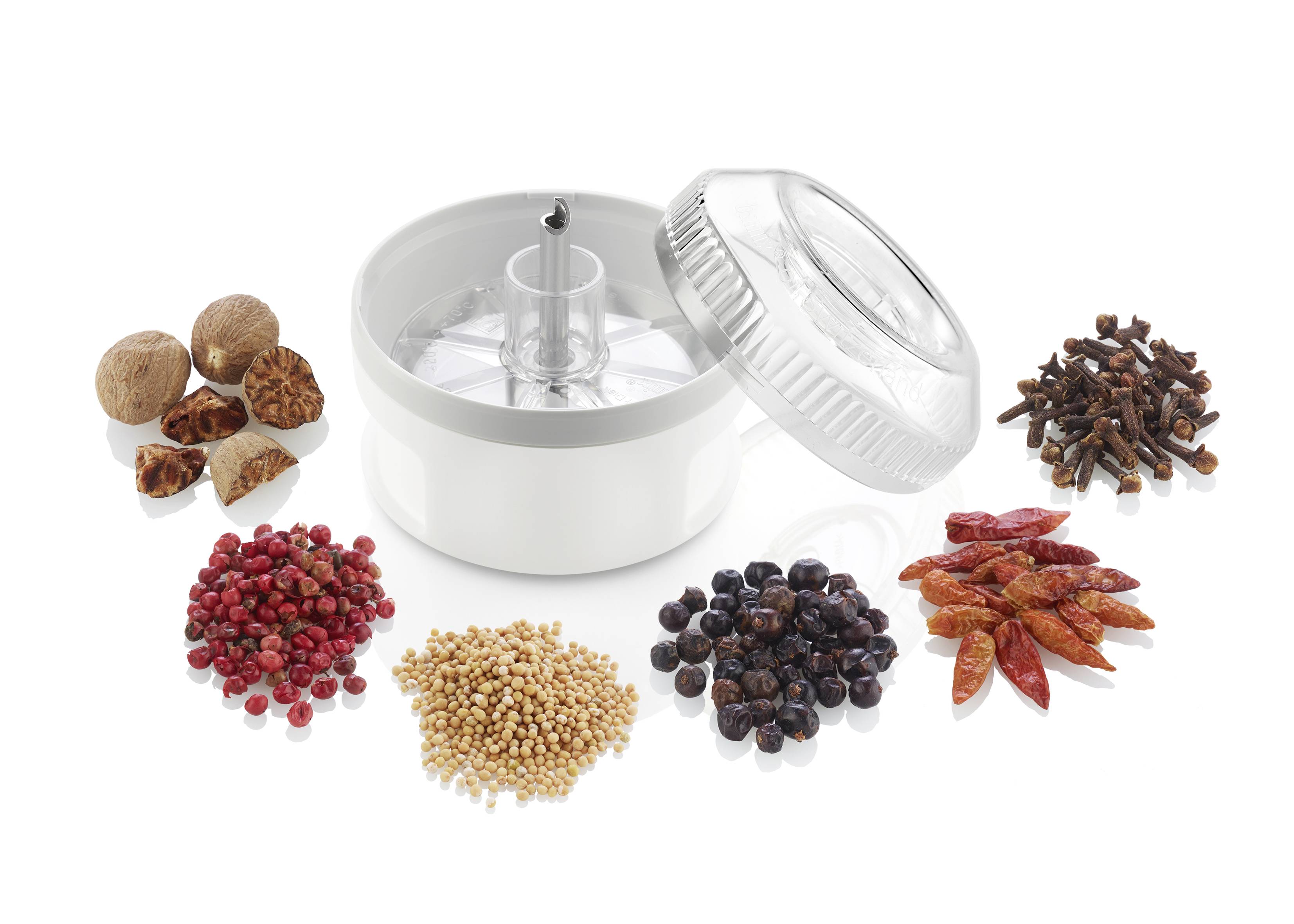 'Grinder with spices such as nutmeg, pink peppercorns, mustard seeds, juniper berries, chilli peppers and cloves on a white background.'