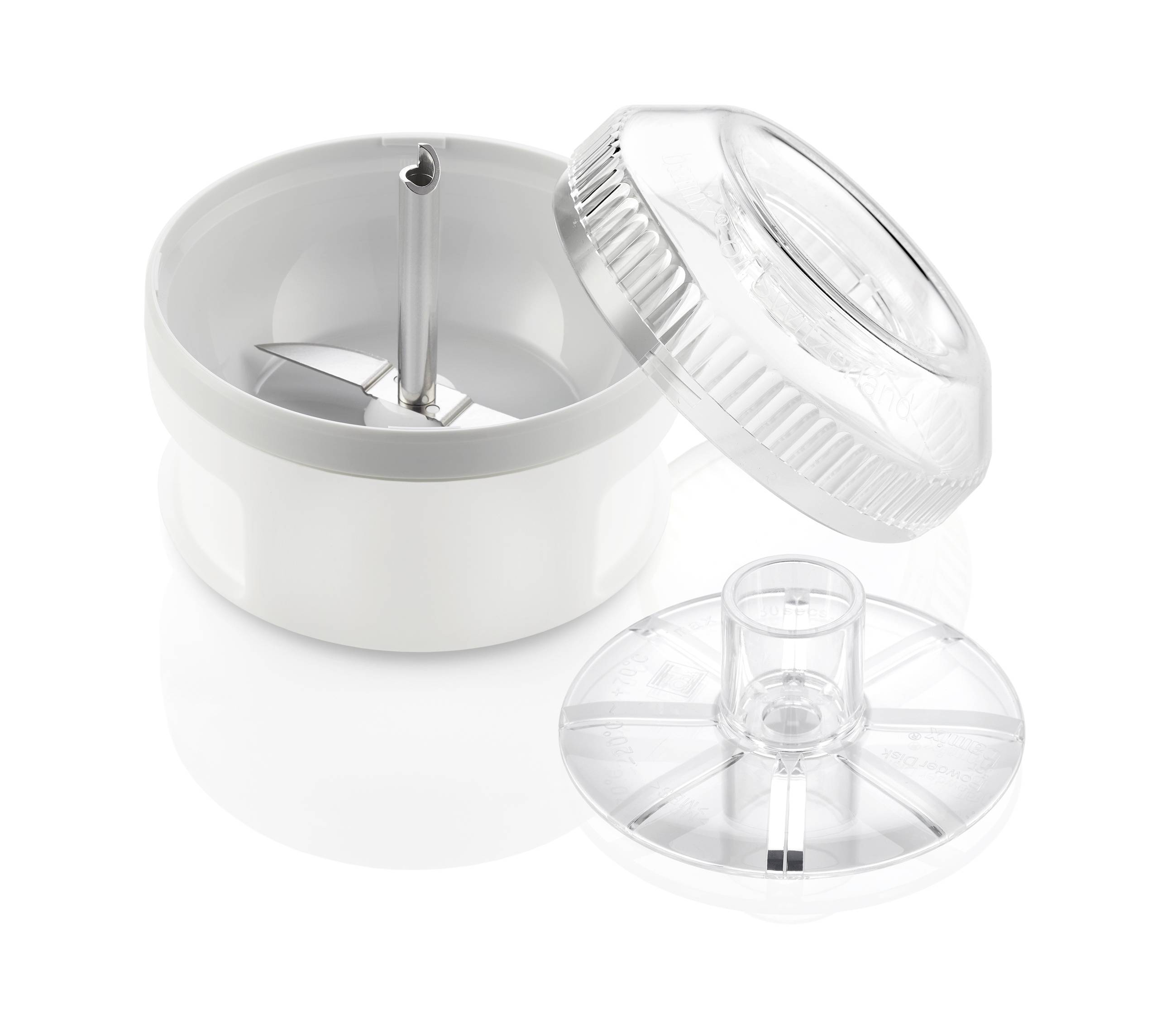 An open, white mixer attachment with visible blades and a removed, transparent lid lies beside it.