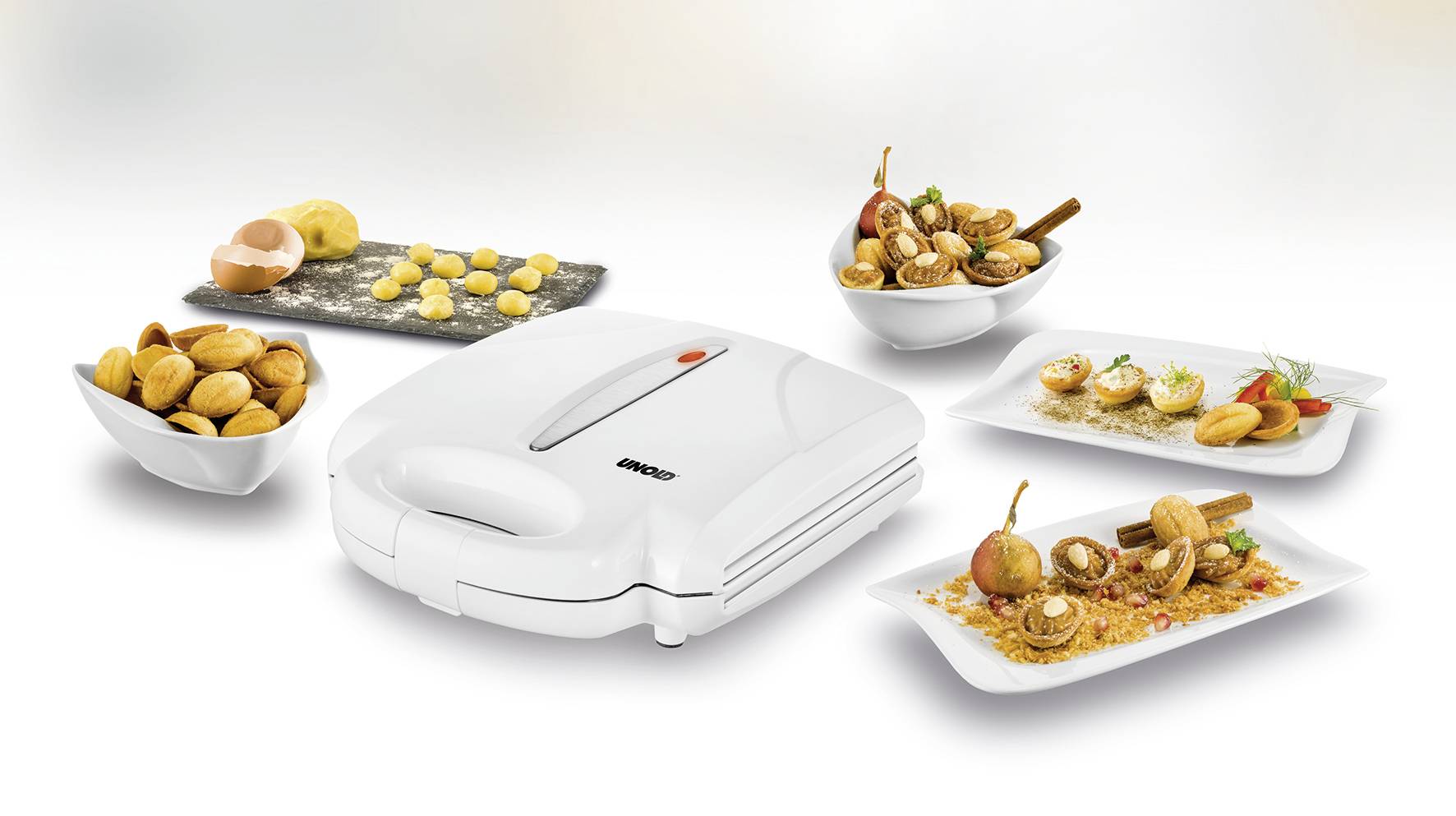 'White kitchen appliance with three plates presenting different biscuits.'