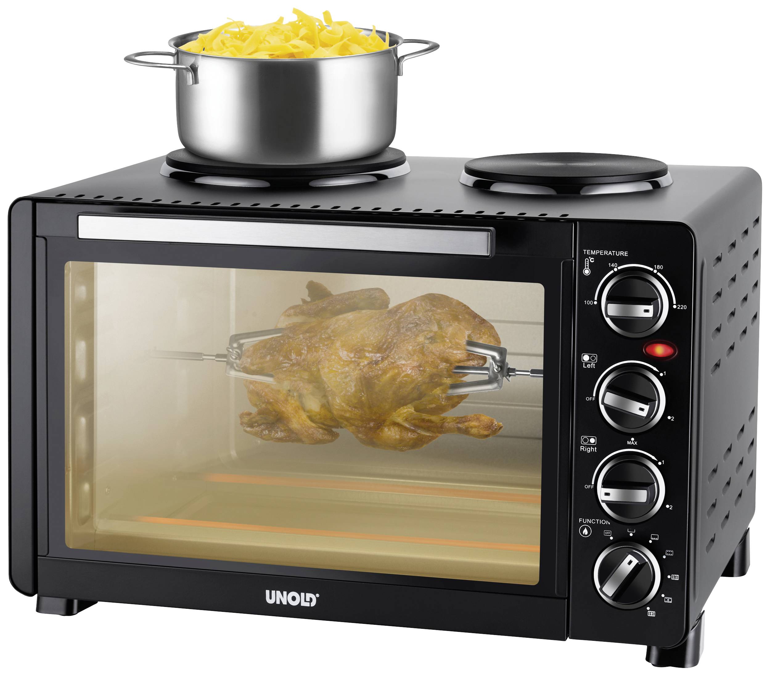 A table oven with a rotisserie is grilling a chicken. A pot with uncooked pasta sits on top of the oven.