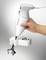 A hand mixer in a person's hand. The device is white with an ergonomic handle. It is shown with metal attachments.