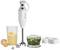 A hand blender set with a mixing wand, a cracked egg, a mixing container with yellow liquid, a chopper with green mixture and accompanying accessories.