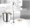 Hand blender next to a pot of soup and a filled plate on a table in a modern kitchen.