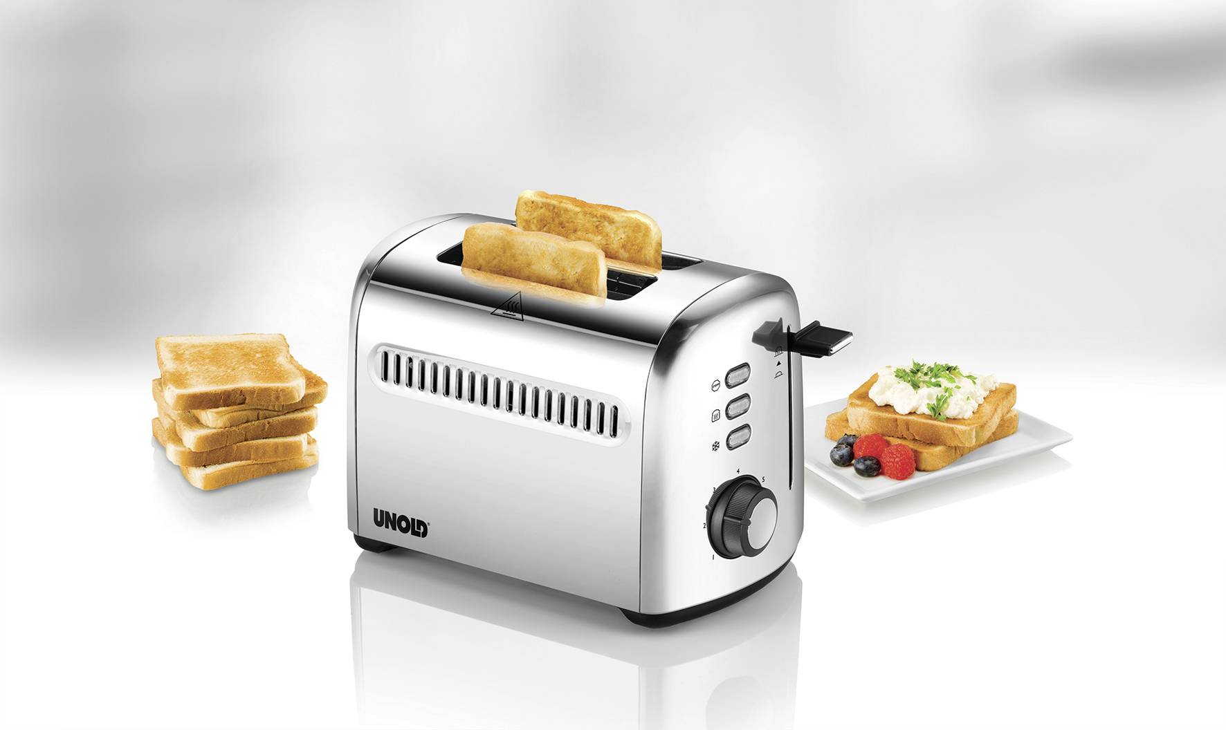 A toaster with two toast slots, a stack of untoasted bread on the left, and a plate with buttered toast and berries on the right.