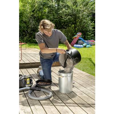 A person is emptying ash into a metal container on a terrace. Green trees and children's toys can be seen in the background.