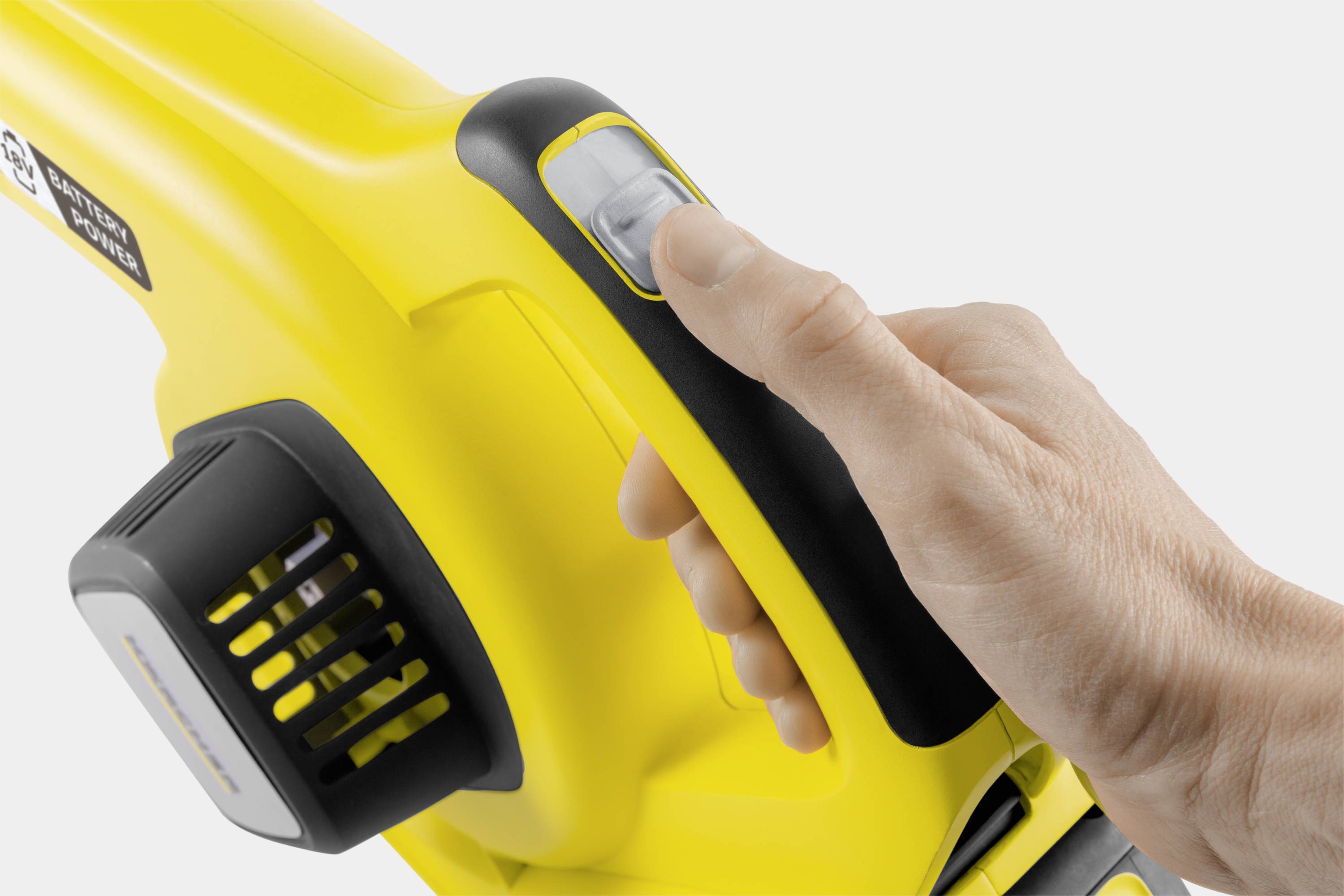 A hand is holding a yellow vacuum cleaner handle and pressing the power button. The vacuum cleaner has a modern design.