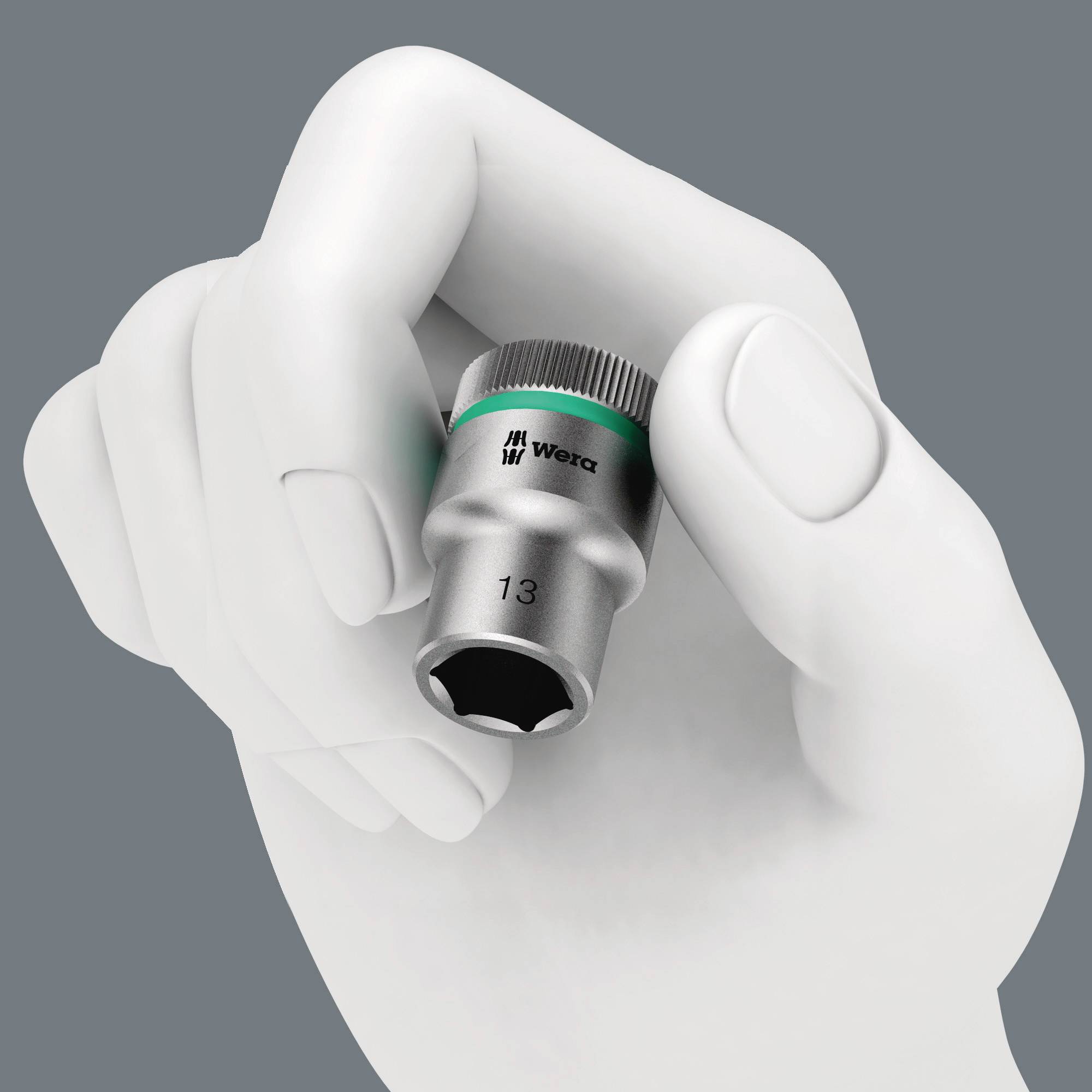 A hand is holding a silver Wera hex socket, size 13. The socket has ridged edges for better grip.