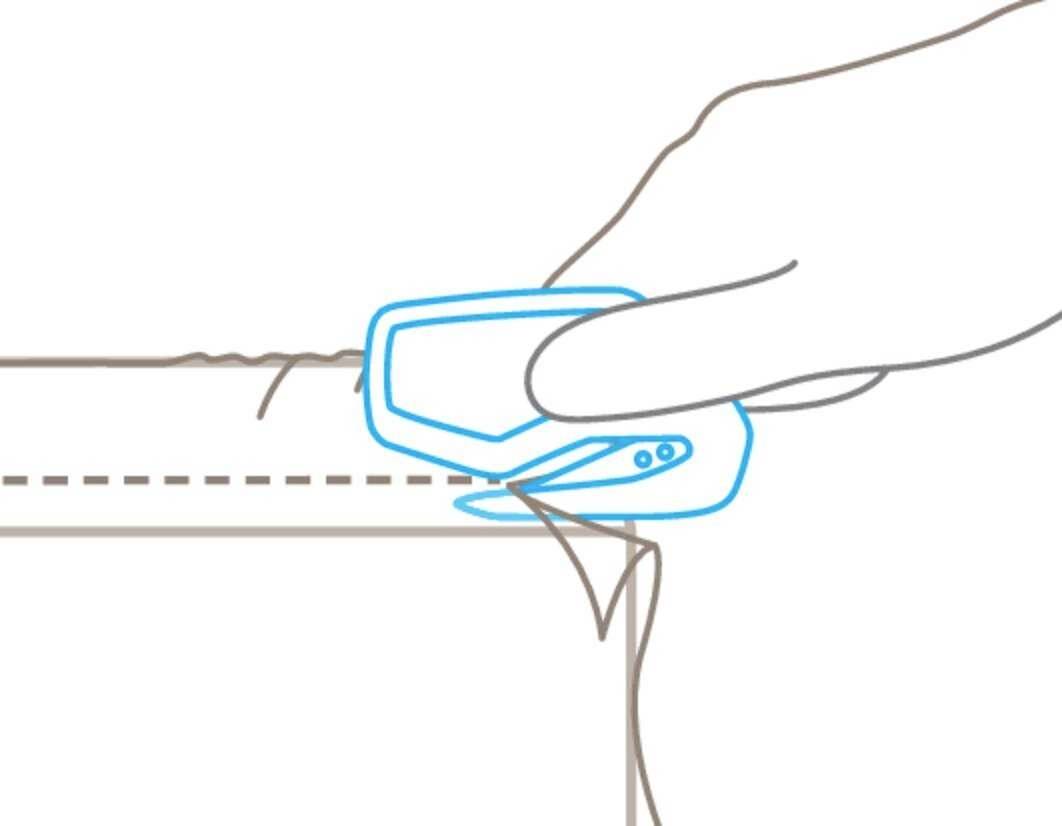 A hand is cutting along a dotted line on cardboard with a craft knife.