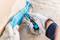 A person is removing a blue seal from a surface using a blue tool. They are wearing white work gloves.