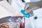 A person wearing a grey glove is cutting white film from a car using a blue cutting tool.