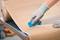 A person wearing gloves is cutting a large roll of brown paper on a table with a blue cutting tool.