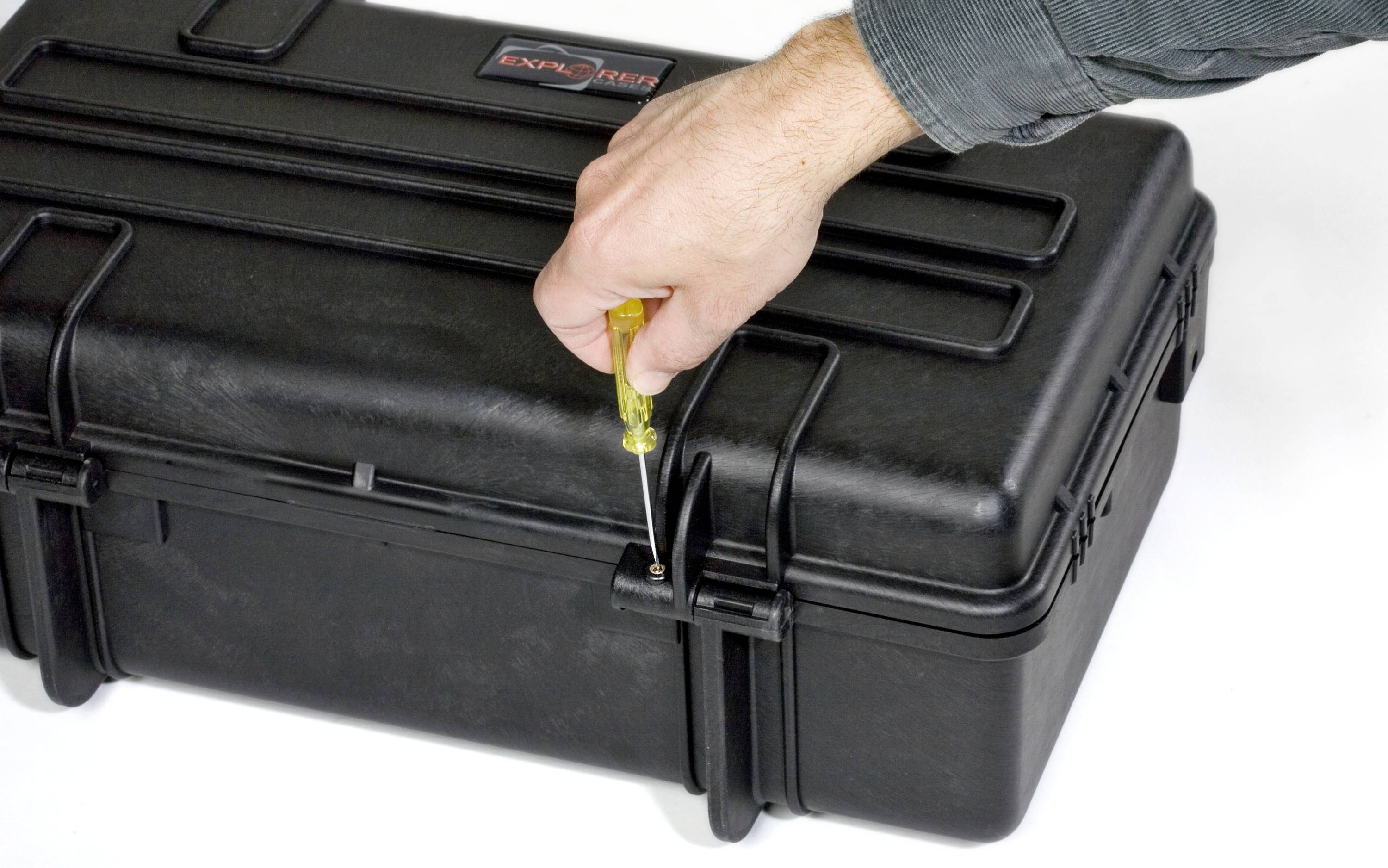 A hand is using a screwdriver to fasten a black, robust toolbox.