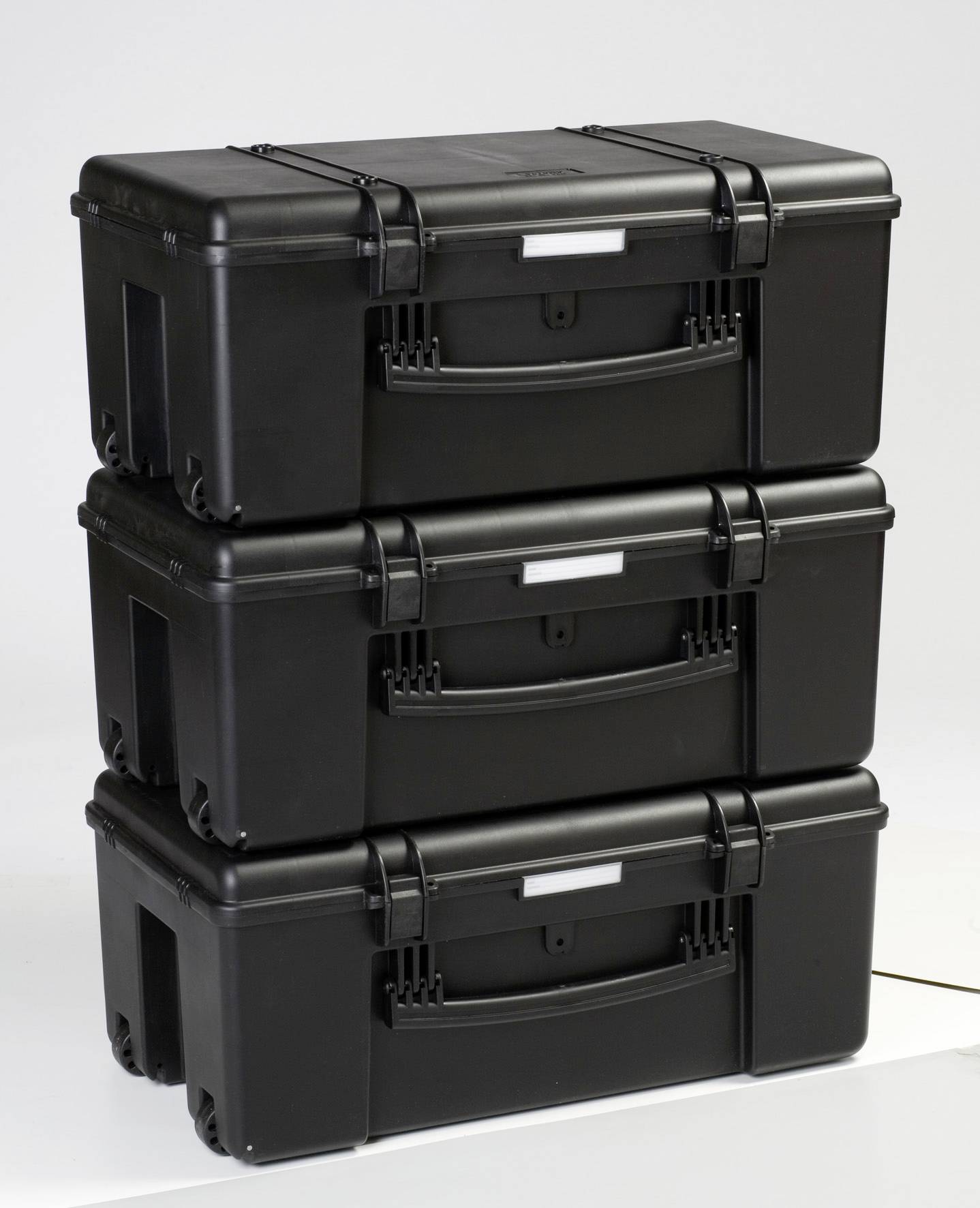Three stacked, black plastic storage boxes with carry handles and label holders, against a white background.