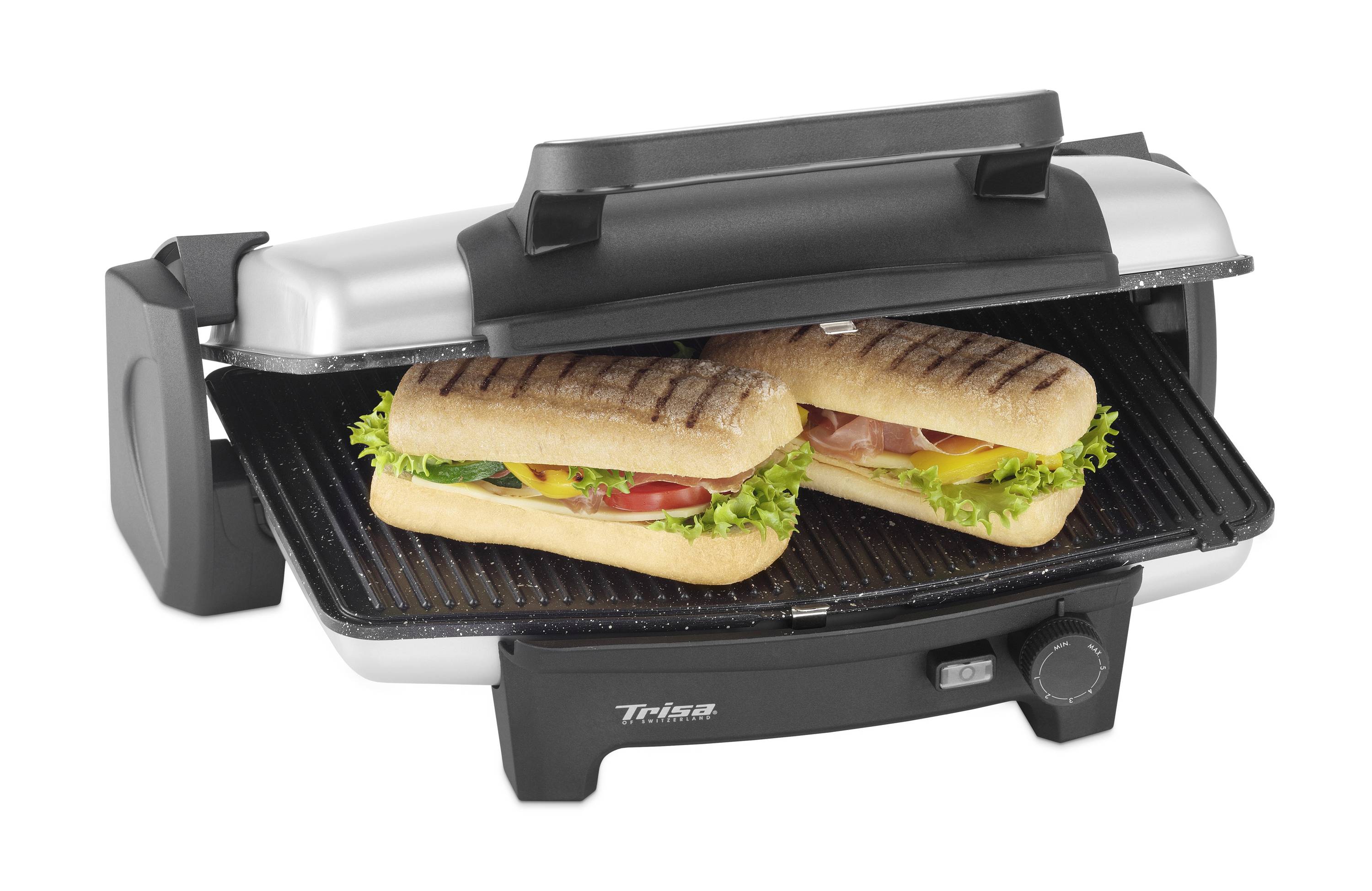 An electric contact grill with two grilled panini sandwiches, filled with lettuce, tomato, and ham.
