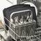 A dishwasher with an open basket shows cutlery in a holder and several black trays in the background.