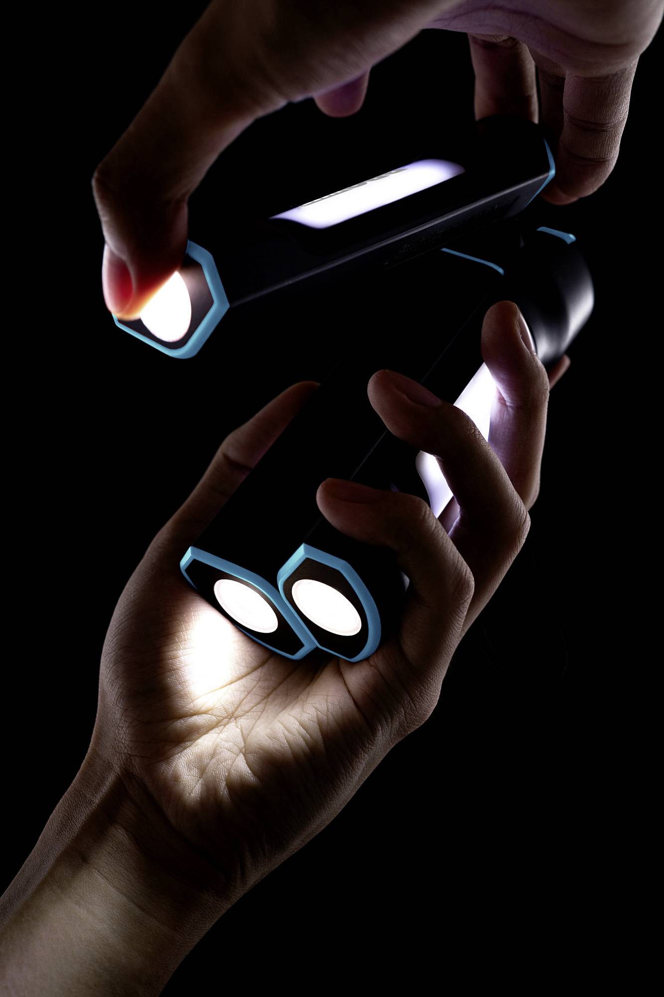 Three hands hold futuristic torches in a dark room. Each torch shines brightly and has a modern, angular design.