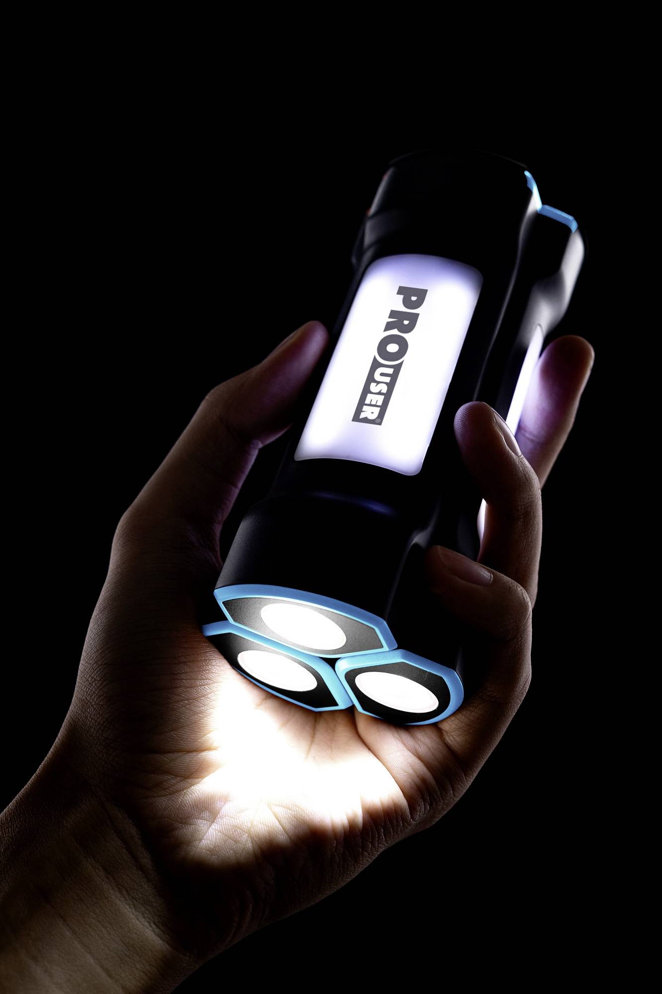 A hand holds a black torch with three illuminating LEDs against a black background.<br><br>Note: In British English, "torch" is used instead of the American "flashlight", and the phrasing is adjusted to sound more natural while preserving the original meaning.