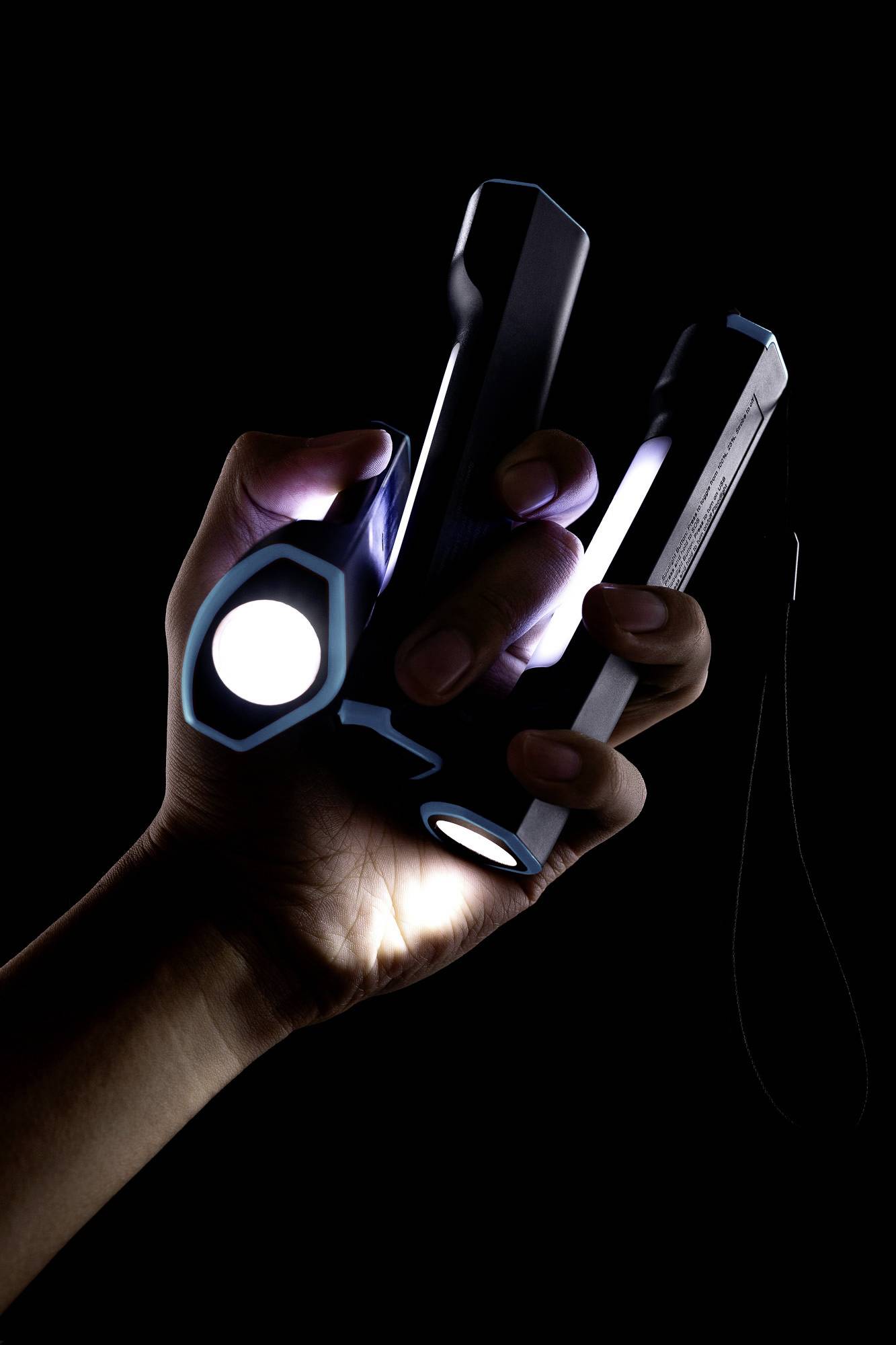 A hand holds three switched-on torches in a dark room, each shining in a different direction.