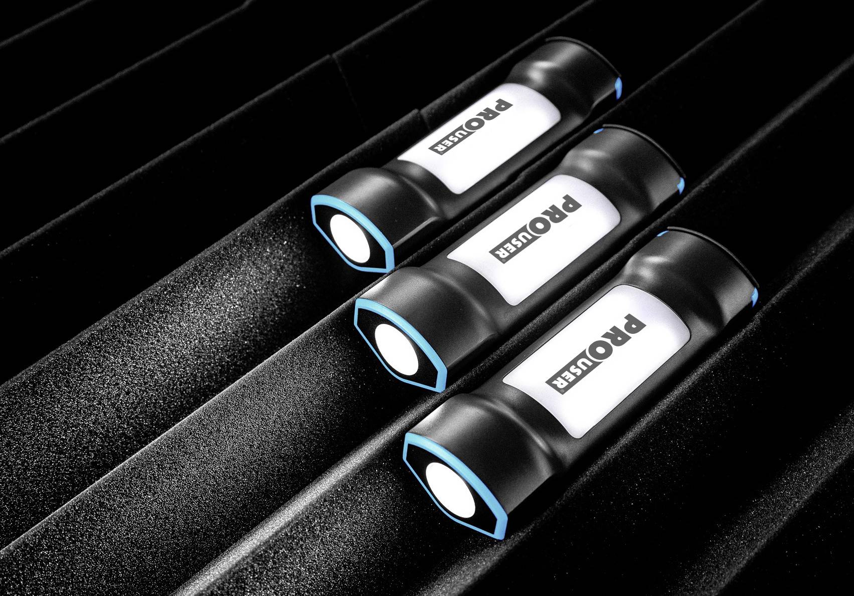 Three black torches with blue edges and 'Prouser' logo lie side by side on a dark textured background.