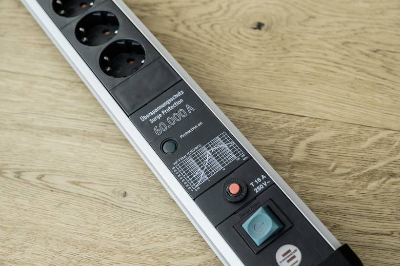 Multi-socket extension with surge protection, 250V, with switchable button and indicator on wooden surface.