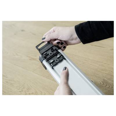 Person adjusting the end cap on a white LED light fixture or strip light on a wooden surface.
