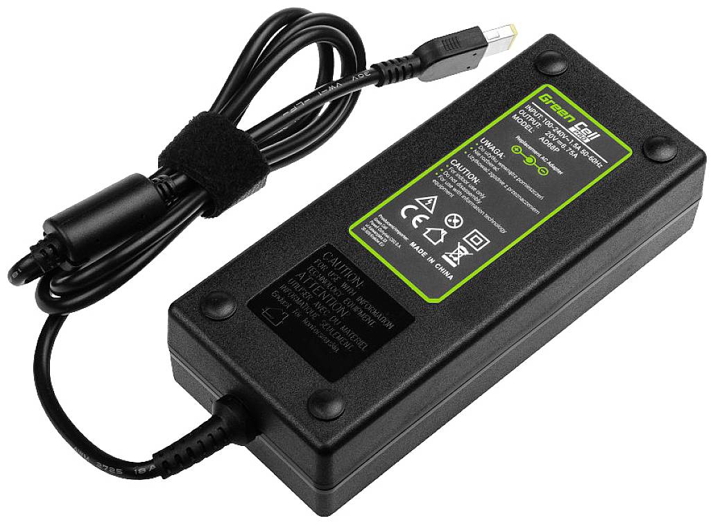 A black laptop power adapter with green markings and safety warnings printed on it. The cable terminates in a small, round plug.