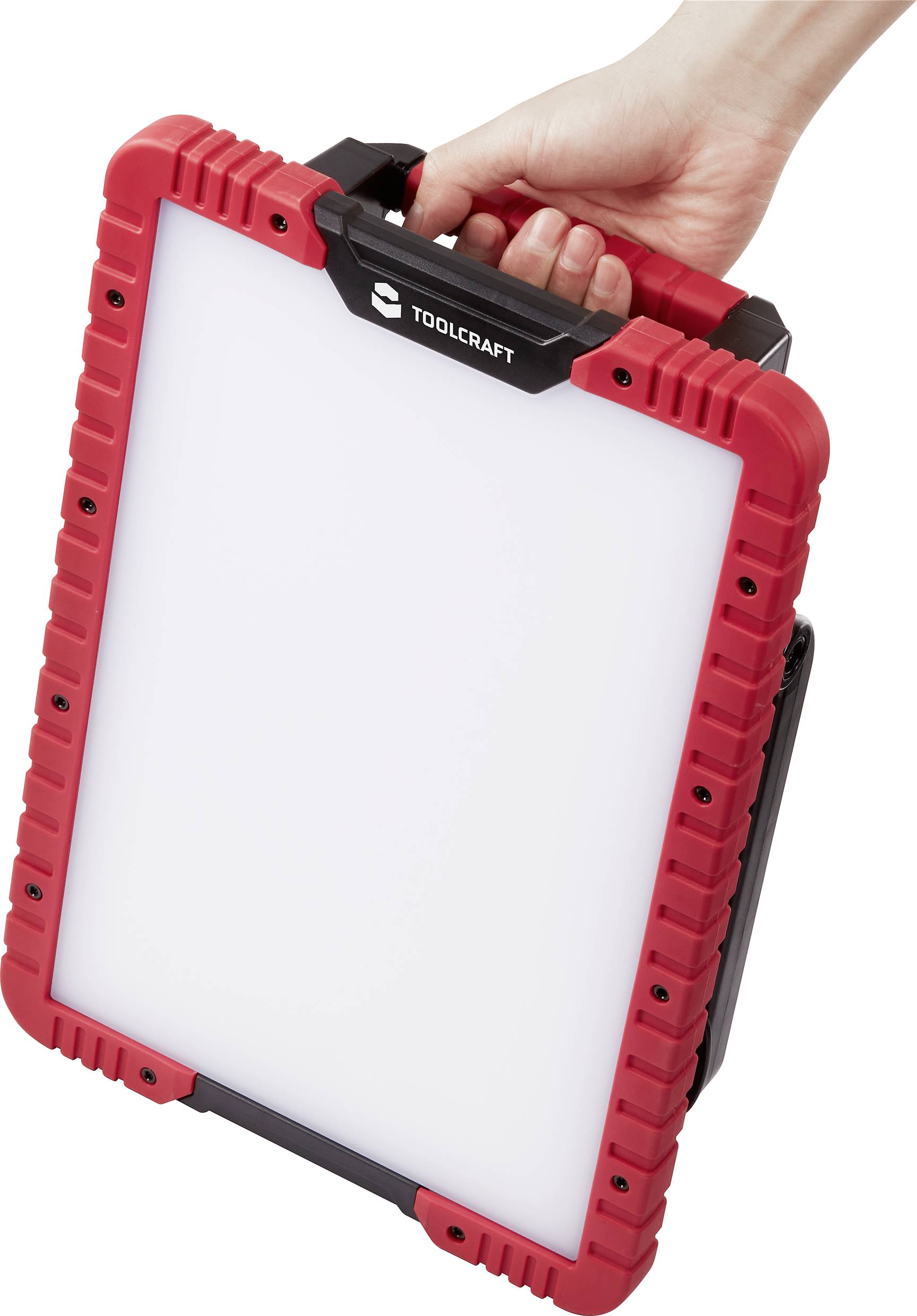 A hand is holding a rectangular, robust Toolcraft lamp with a red border and black handle.
