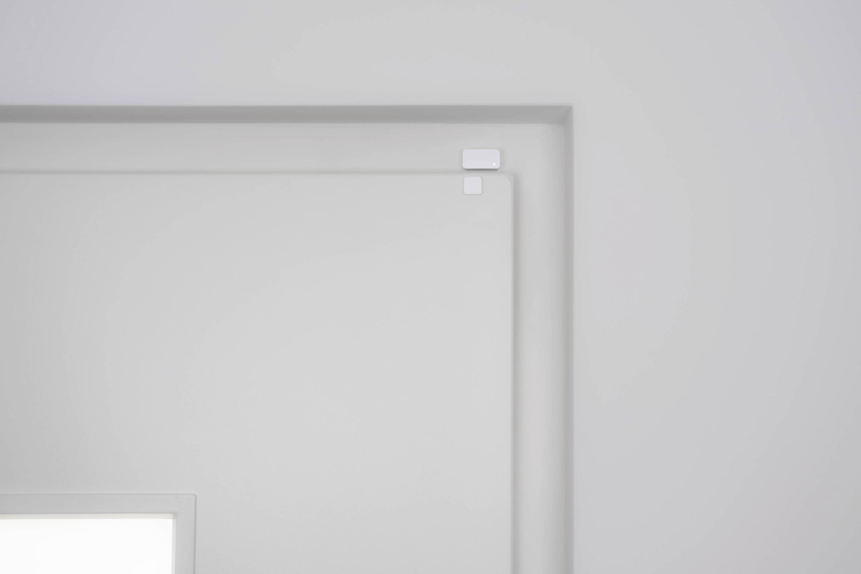 White, minimalist room ceiling with square design elements in the corners.