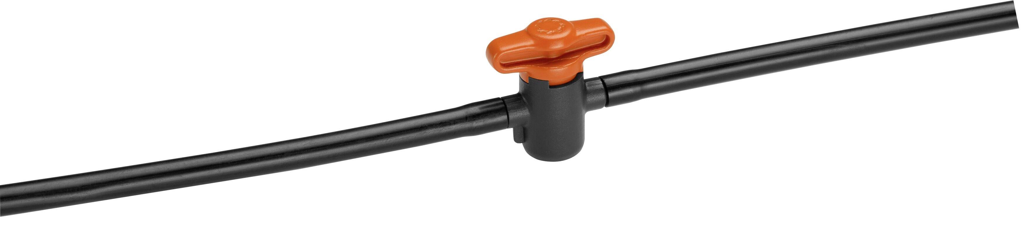 Black irrigation pipe with a red shut-off valve in the middle. Valve for controlling water flow in a garden irrigation system.