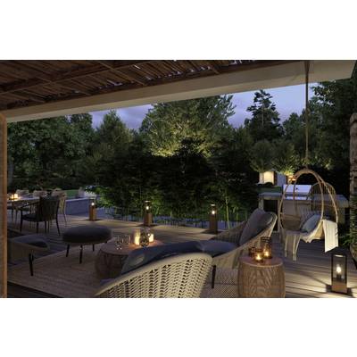 A terrace at dusk, cosily furnished with chairs, a table and candles. In the background, an illuminated garden.