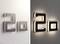 Two stylised, illuminated 3D numbers '20' on a wall, each depicted in lighter and darker colour tones.