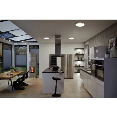 Modern kitchen with dining area; large windows, wood-burning stove, light worktops, stainless steel appliances and a table with black chairs.