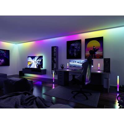 A modernly furnished gaming room with multi-coloured LED lighting. A large screen and a gaming chair are visible.