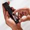 A hand is inserting two AA batteries into the open back of a remote control. The batteries are labelled 'Energizer'.