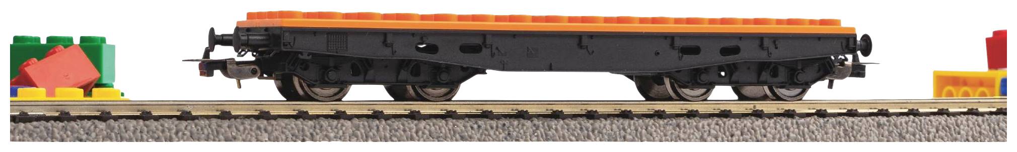 A railway carriage made of black Lego bricks with an orange upper edge stands on a track, surrounded by coloured building blocks.