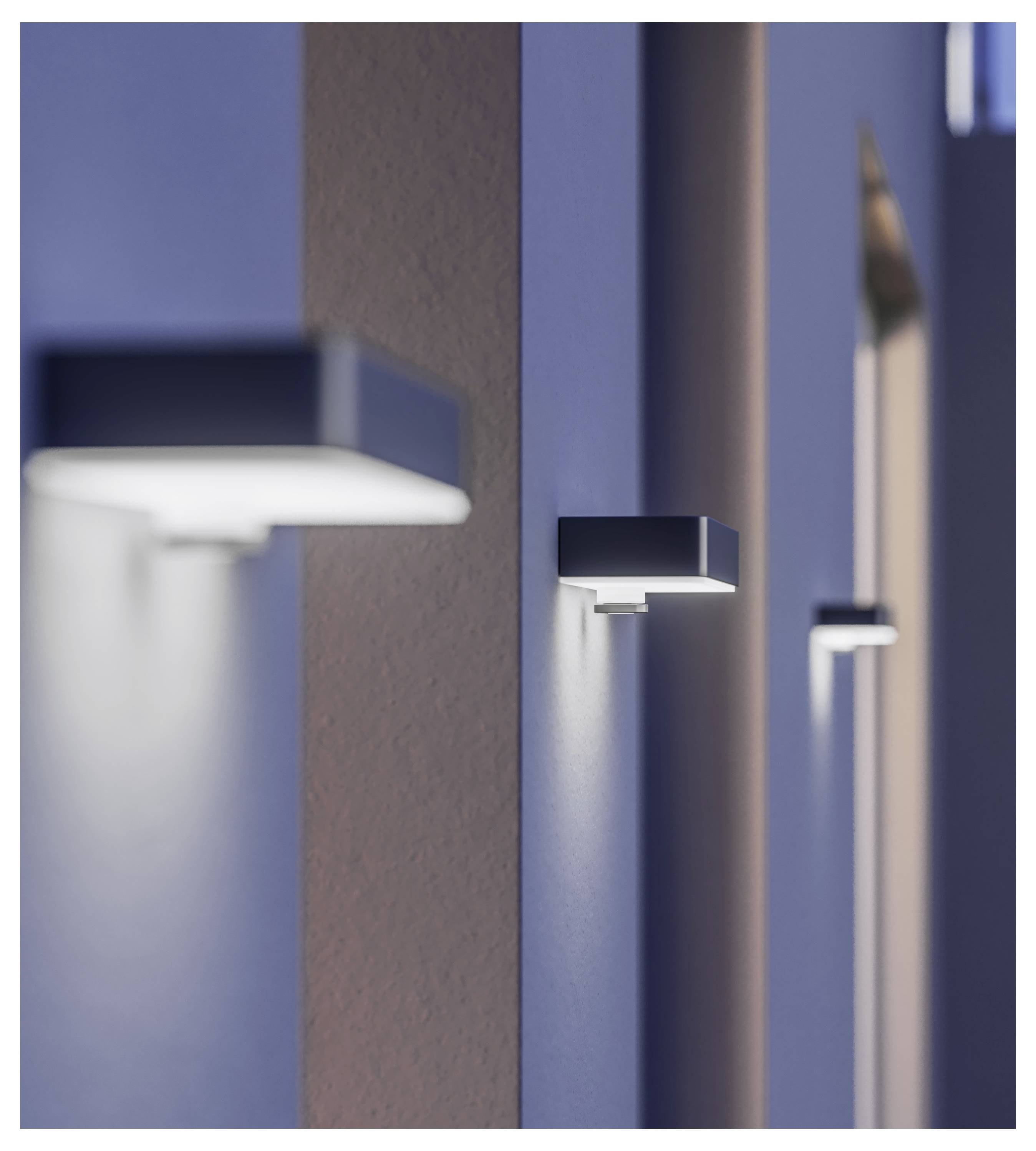 Wall-mounted rectangular lights casting narrow beams of light on a hallway or exterior wall at night.