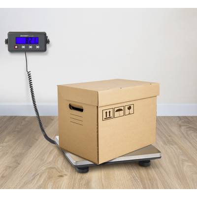 A brown cardboard box is being weighed on a scale. The digital display shows a weight of 8.21 kg.