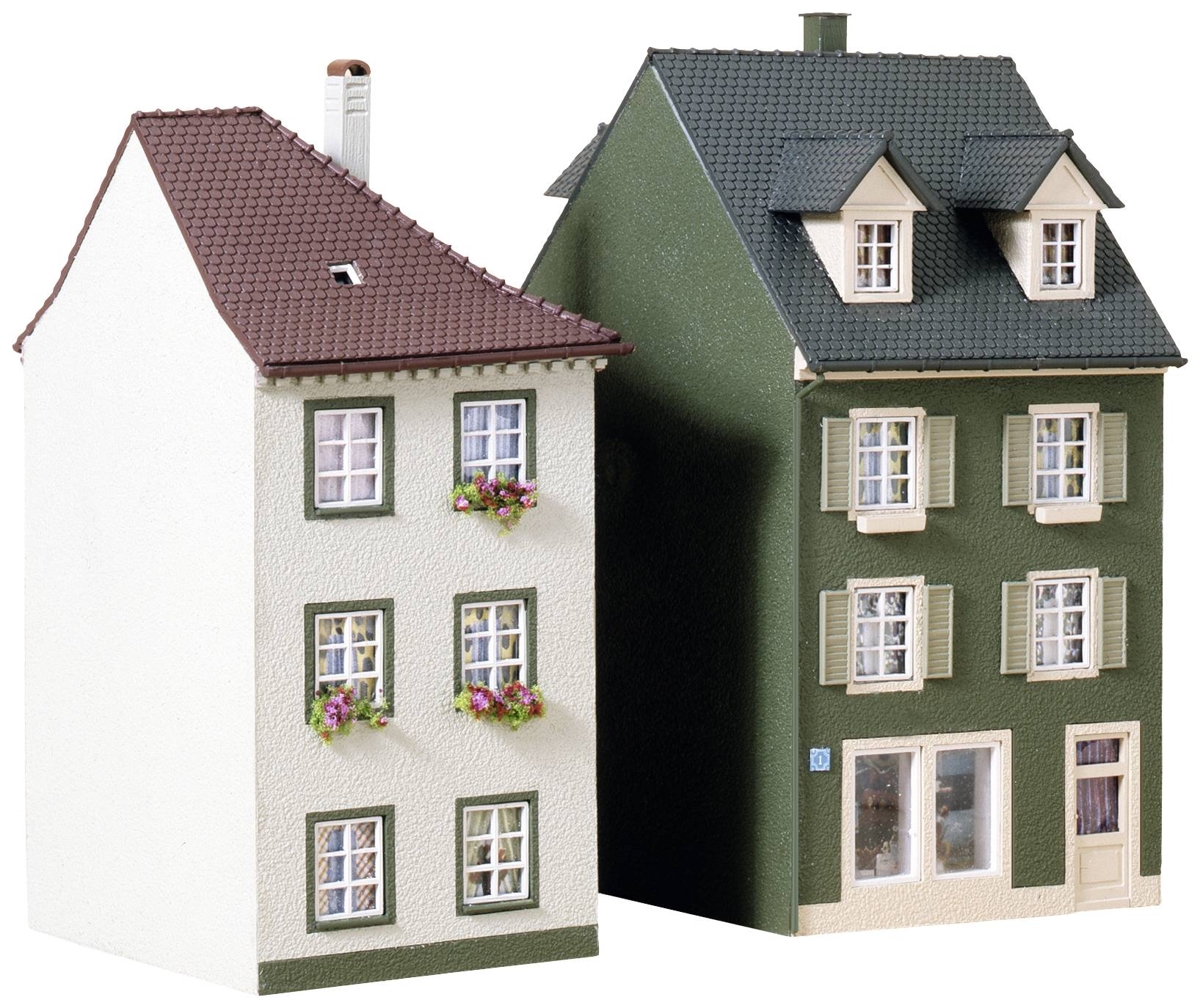 Two miniature houses made of plastic, side by side. On the left, a white house with a red roof and flowers at the windows, on the right a green one with a chimney.