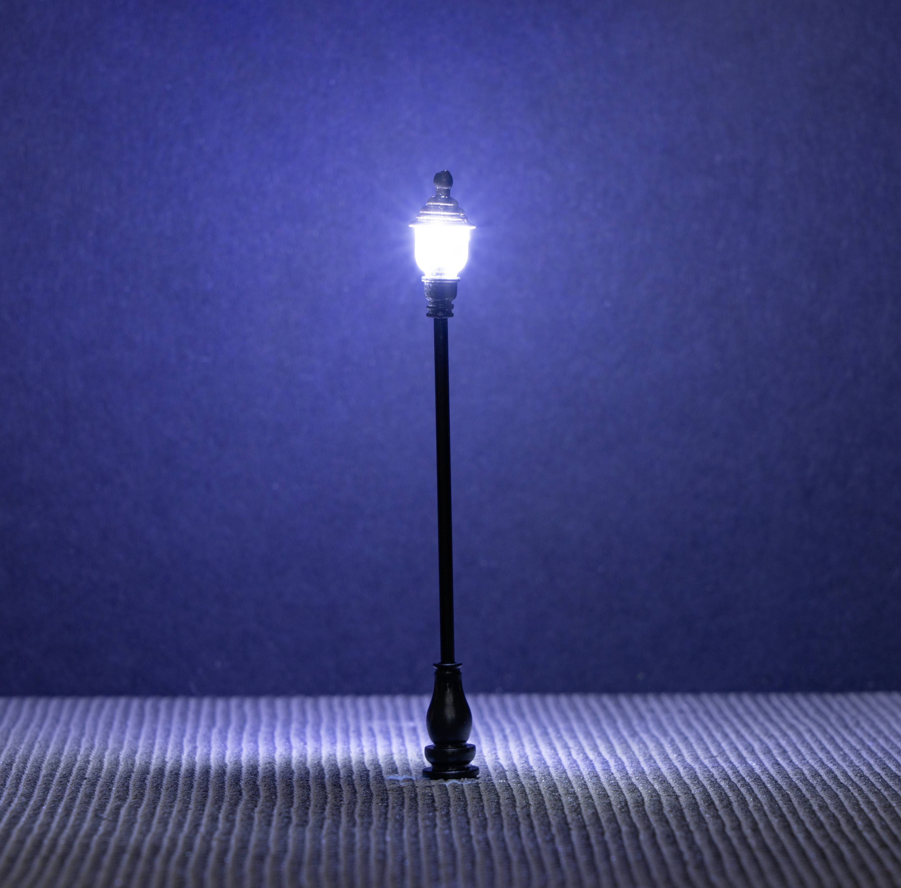 A single street lamp shines brightly in the darkness on a textured surface against a deep blue background.