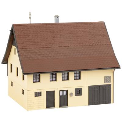 Two-storey model building with a red pitched roof, yellow walls, multiple windows, and a large, dark door on the right.