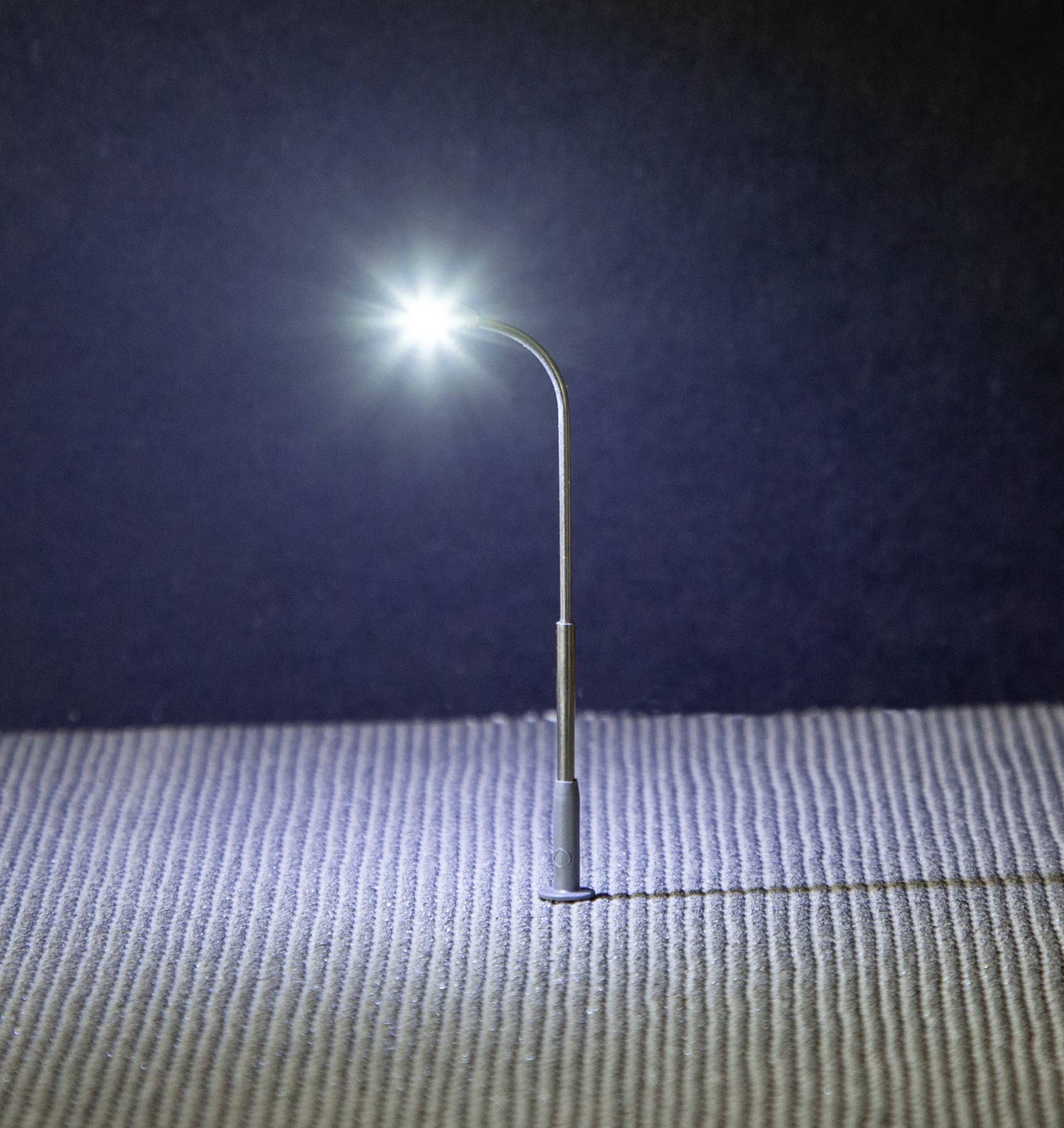 A small model of a street lamp lights up on a textured surface, illuminating the area around it.
