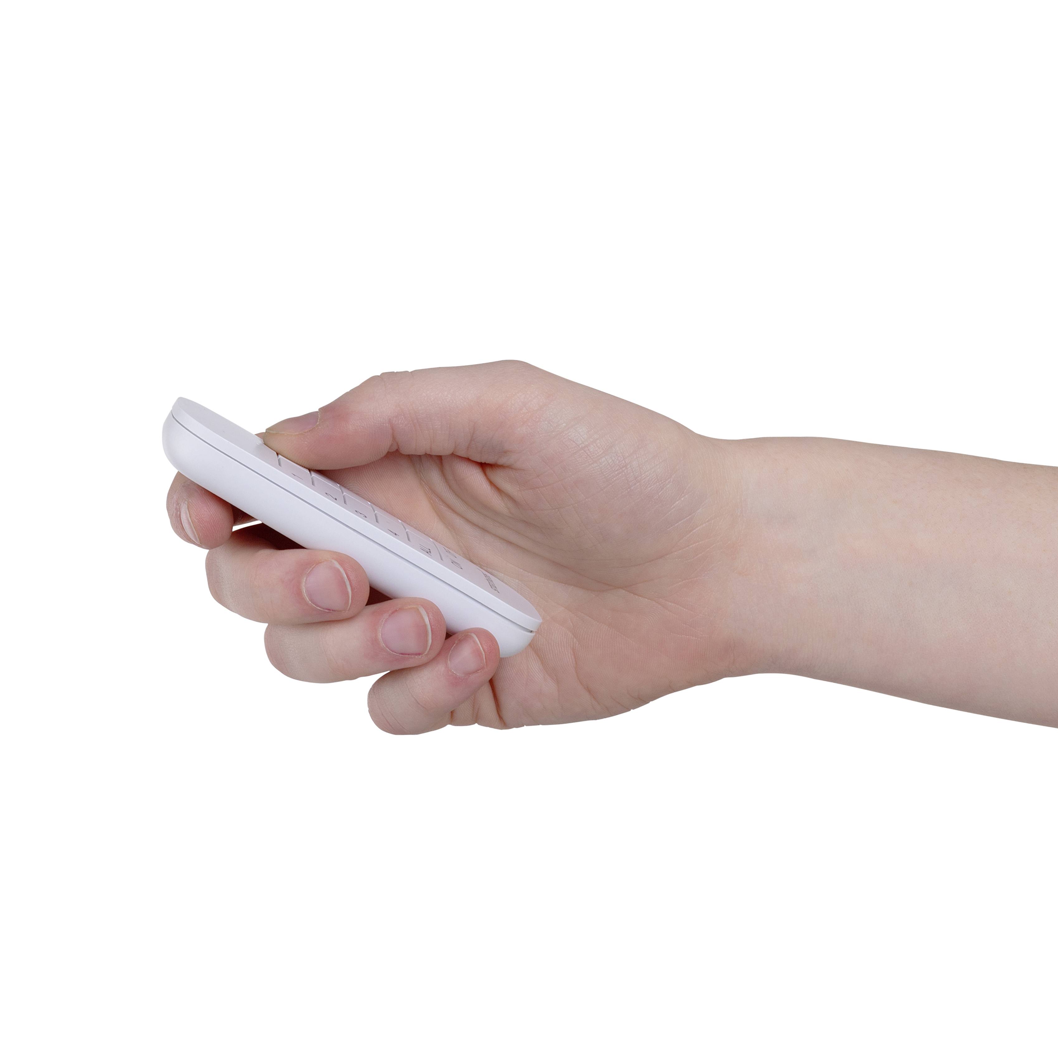 A hand is holding a white remote control pointing downwards.