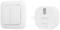 A white wall switch next to a Smartwares receiver, both in a minimalist design. The switch has two buttons, and the receiver features an LED display.