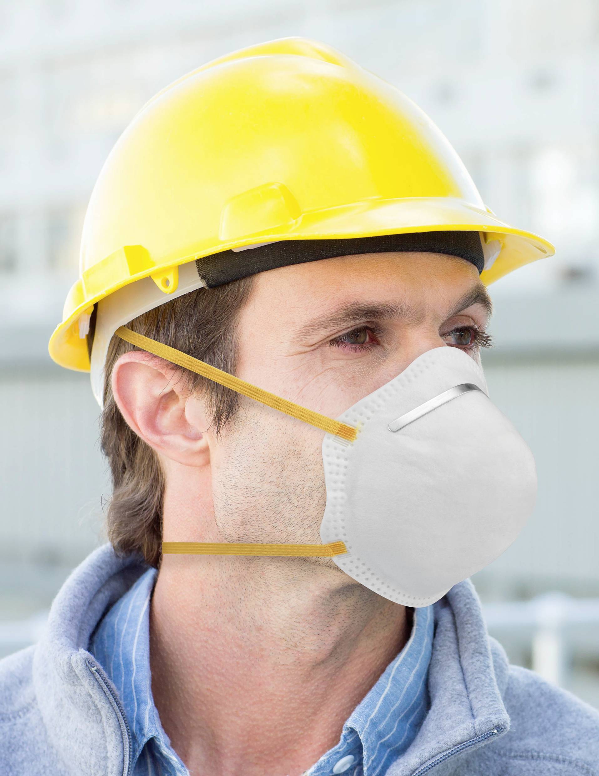 A construction worker wearing a yellow hard hat and white face mask is looking to the right. The background shows construction site elements.